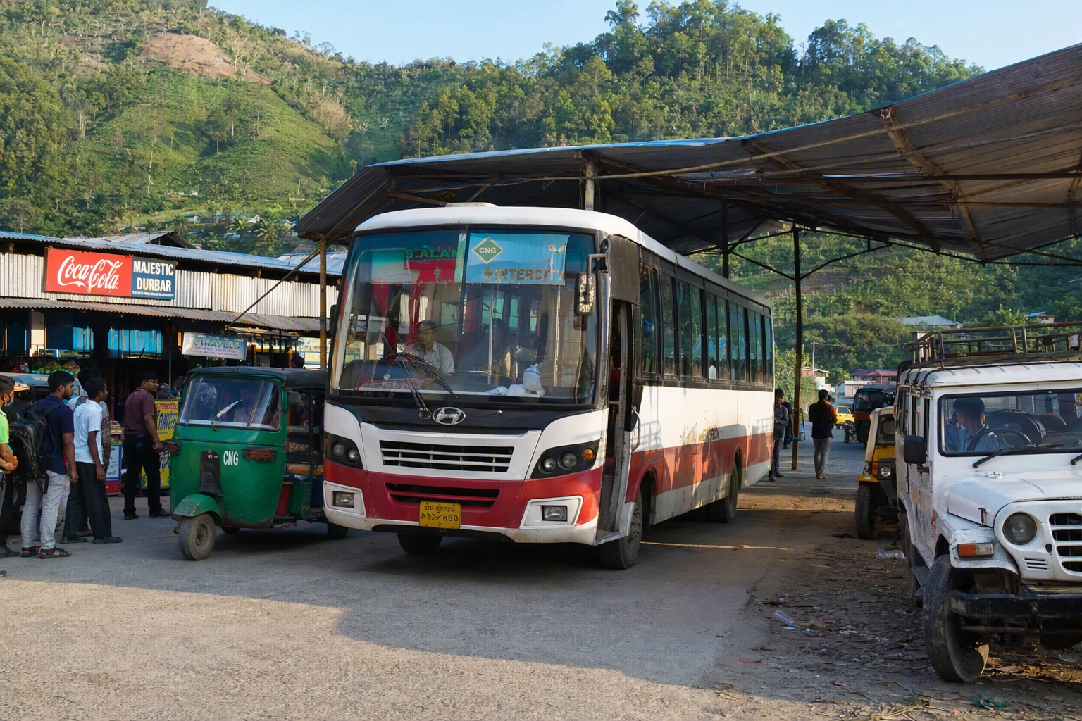An intercity bus arriving at a Hill Tracts town terminal beside shared local vehicles