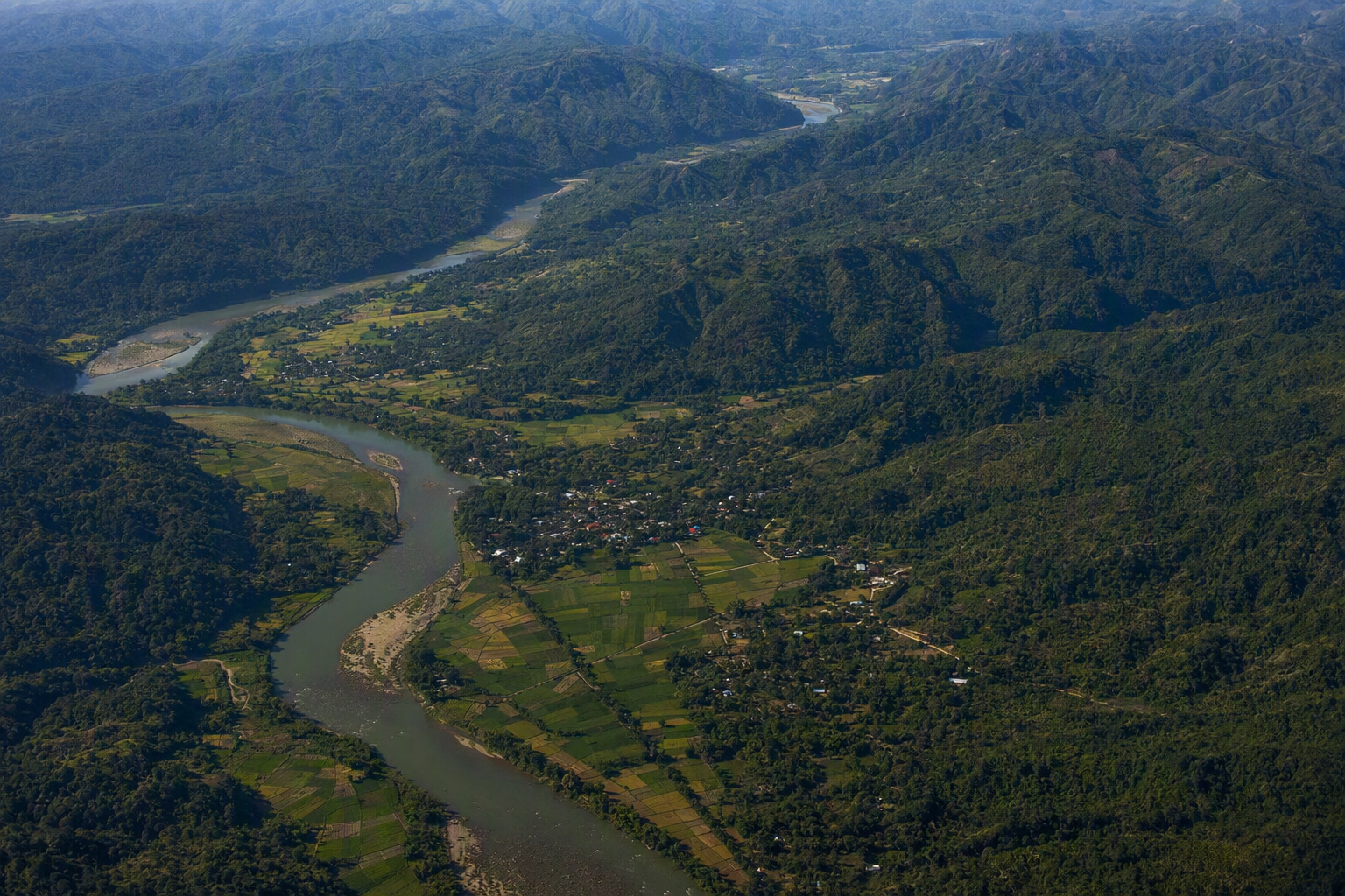 Oblique aerial view of forested Hill Tracts ridges, a winding river, farms and small settlements