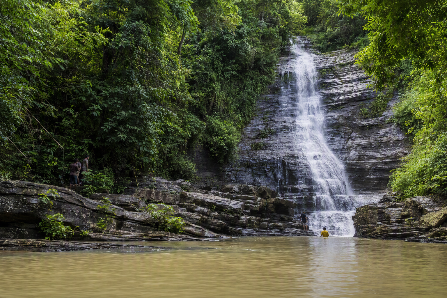 Shuvolong Waterfall descending over dark rock into Kaptai Lake during the wet season